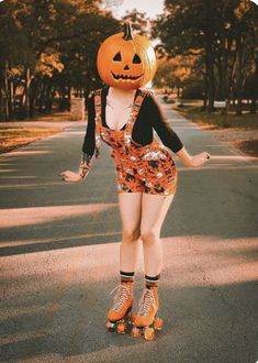 a woman riding on top of a skateboard wearing a pumpkin costume