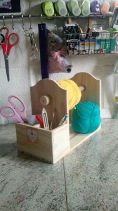 scissors, yarn and other crafting supplies in a wooden holder