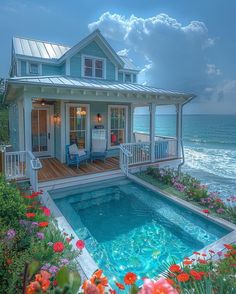 a small house next to the ocean with a pool in front of it and flowers growing on the ground