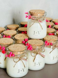 there are many small jars with pink flowers in them on the table next to each other