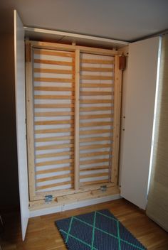 an empty room with wooden slats on the wall and a blue rug in front of it