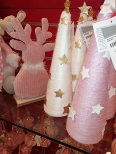 pink and white christmas trees with gold stars are on display in a store window for sale