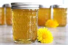 a jar filled with honey sitting on top of a table next to a yellow flower