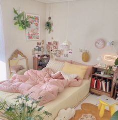 a bed with pink comforter and pillows in a small room next to a window