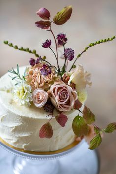 a close up of a cake with white frosting and pink flowers on the top