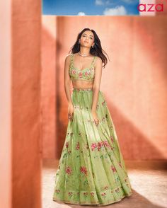 a woman in a green lehenga and matching crop top is posing for the camera