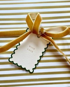 a gift wrapped in yellow ribbon with a white tag on it that says with love