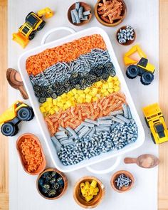 a tray filled with lots of different types of toy cars and trucks on top of a table