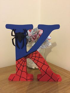 a wooden table topped with a vase filled with flowers and a spiderman figure next to it