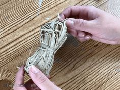 two hands holding twine on top of a wooden table