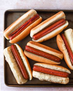 six hot dogs in buns on a tray