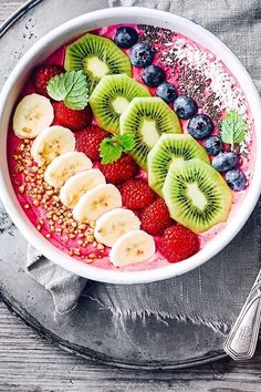 a bowl filled with fruit and granola topped with kiwis, strawberries, blueberries