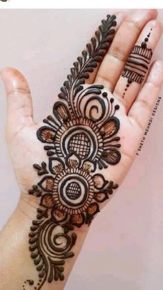 a woman's hand with henna tattoos on it, showing the intricate design