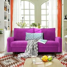 a living room with a purple couch and coffee table in front of two large windows