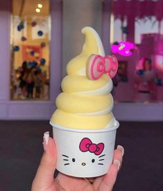 a hand holding an ice cream cone with hello kitty on top