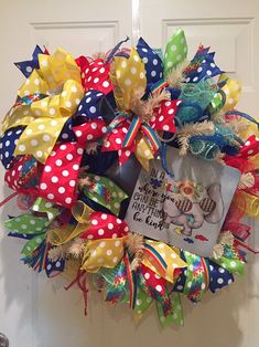 a colorful wreath is hanging on the front door with a book and bow tie around it