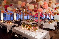 a dining room filled with lots of tables covered in white tablecloths and centerpieces