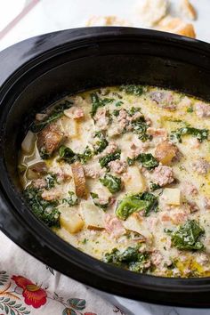 a casserole dish with meat, cheese and spinach in a black crock pot