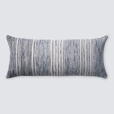 a gray and white striped pillow on a grey background