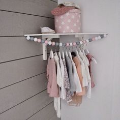 a rack with clothes hanging from it's sides next to a wall and a bucket