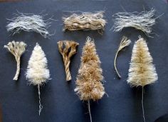 several different types of rope and grass on a black tablecloth with white thread attached to them