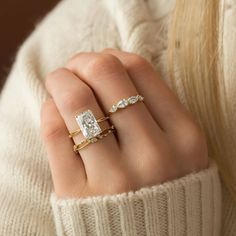 a woman's hand with two rings on her fingers, one in gold and the other in white