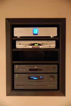 an entertainment system mounted on the wall with remotes and other electronic equipment in it