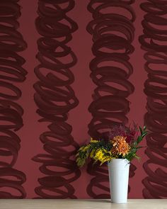 a vase filled with flowers sitting on top of a wooden table next to a wall