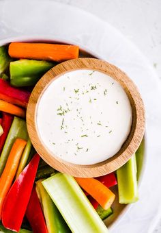 carrots, celery, and other vegetables in a bowl with a dip