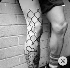 a man with tattoos on his legs standing next to a brick wall