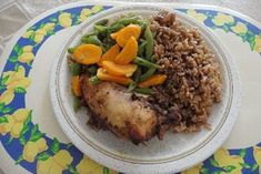 a white plate topped with meat, rice and veggies on top of a blue and yellow table cloth