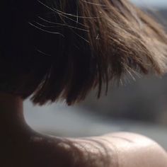 a close up of a person's head with hair blowing in the wind and blurry background