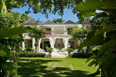 a large white house surrounded by lush green trees