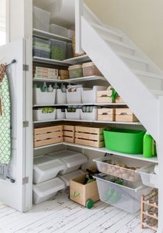 an organized pantry under the stairs in a room with white walls and wooden flooring