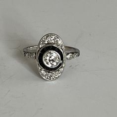 Old platinum ring from the years 1925-1930, oval tray centered with a closed-set diamond in an entourage of calibrated onyx and diamonds. Openwork basket, frame set with diamonds. Total diamond weight: approximately 0.80 ct, beautiful colour. Plate: 18 x 12 mm Gross Weight: 3.90g. Size: 51.5 Possibility of resizing, contact us. Further information : We issue an invoice as well as a certificate of authenticity established by our qualified gemologist (LFG Paris). Our photos are not reworked and ar Art Deco Oval Platinum Diamond Ring, Classic Platinum Oval Cabochon Ring, Classic Black Enamel Oval Ring, Classic Oval Black Enamel Ring, Art Deco Oval Diamond Ring With Accents, Art Deco Oval Rings With Rose Cut Diamonds, Collectible Oval Art Deco Diamond Ring, Classic White Gold Diamond Ring With Oval Cabochon, Art Deco Oval Ring With Center Stone