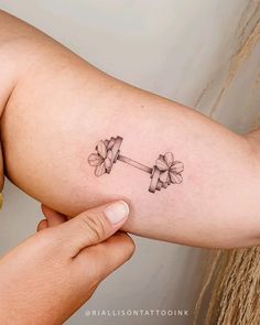 a woman's arm with a tattoo on it that has flowers attached to the barbells