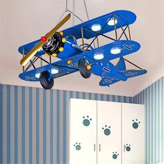 a toy airplane hanging from the ceiling in a room with blue walls and striped wallpaper