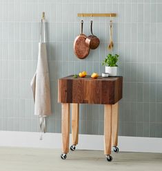 a wooden table with two pots and pans hanging on the wall next to it