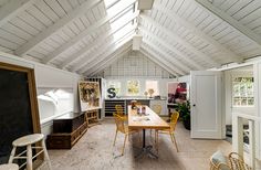 a room with a table, chairs and a chalkboard on the wall in it