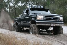 a large black truck driving down a dirt road