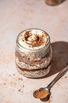 a spoon is sitting next to a jar of chia pudding with cinnamon on top