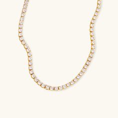 The Eternal Radiance Tennis Necklace shines with timeless elegance, featuring a row of dazzling diamond simulants set in 18K gold. This piece embodies the perfect balance of luxury and simplicity, making it ideal for special occasions or adding a touch of glamour to everyday wear. With its radiant sparkle and sleek design, this necklace is crafted to catch the light from every angle, ensuring you stand out with sophistication and grace. A must-have addition to any jewelry collection. Composition:Ethically sourced Stainless Steel-Plated 18k Gold and AAAAA Diamond Simulants.Water, Sweat, and Heat Resistant. (No discoloration, No Tarnishing).Hypoallergenic and skin-friendly.Comes in an eco-friendly package.Measurement:Length: 14 InchesWeight: 7.6 g Timeless Cubic Zirconia Tennis Necklace For Anniversary, Classic Tennis Necklace In Diamond White Cubic Zirconia, Classic Crystal Tennis Necklace With Prong Setting, Classic Diamond Tennis Necklace With Sparkling Stones, Classic Cubic Zirconia Tennis Necklace With Prong Setting, Classic Crystal Tennis Necklace, Timeless Cubic Zirconia Tennis Necklace With Prong Setting, Classic Everyday Cubic Zirconia Necklace, Classic Gold Necklace With Sparkling Stones