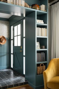 a room with blue walls and bookshelves in the corner, along with a yellow chair