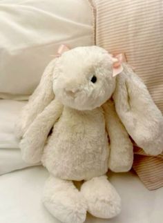 a white stuffed rabbit sitting on top of a bed