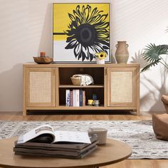 a living room scene with focus on the coffee table and entertainment center, which has a sunflower painting on the wall