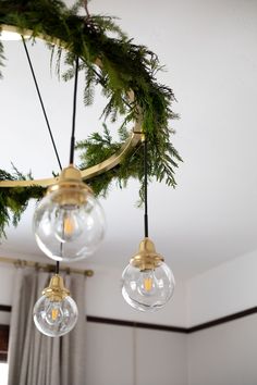 three glass globes hanging from a chandelier in a room with white walls