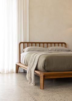 a bed with a wooden headboard and foot board in a bedroom next to a window