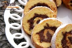 several pastries on a white plate with chocolate swirls and powdered sugar in the middle