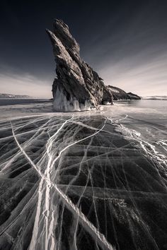 an ice - covered rock in the middle of water with snow and ice on it