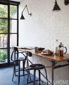 a table with food and drinks on it in front of a brick wall that reads house & home